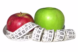 Red and green apples wrapped in a tape measure